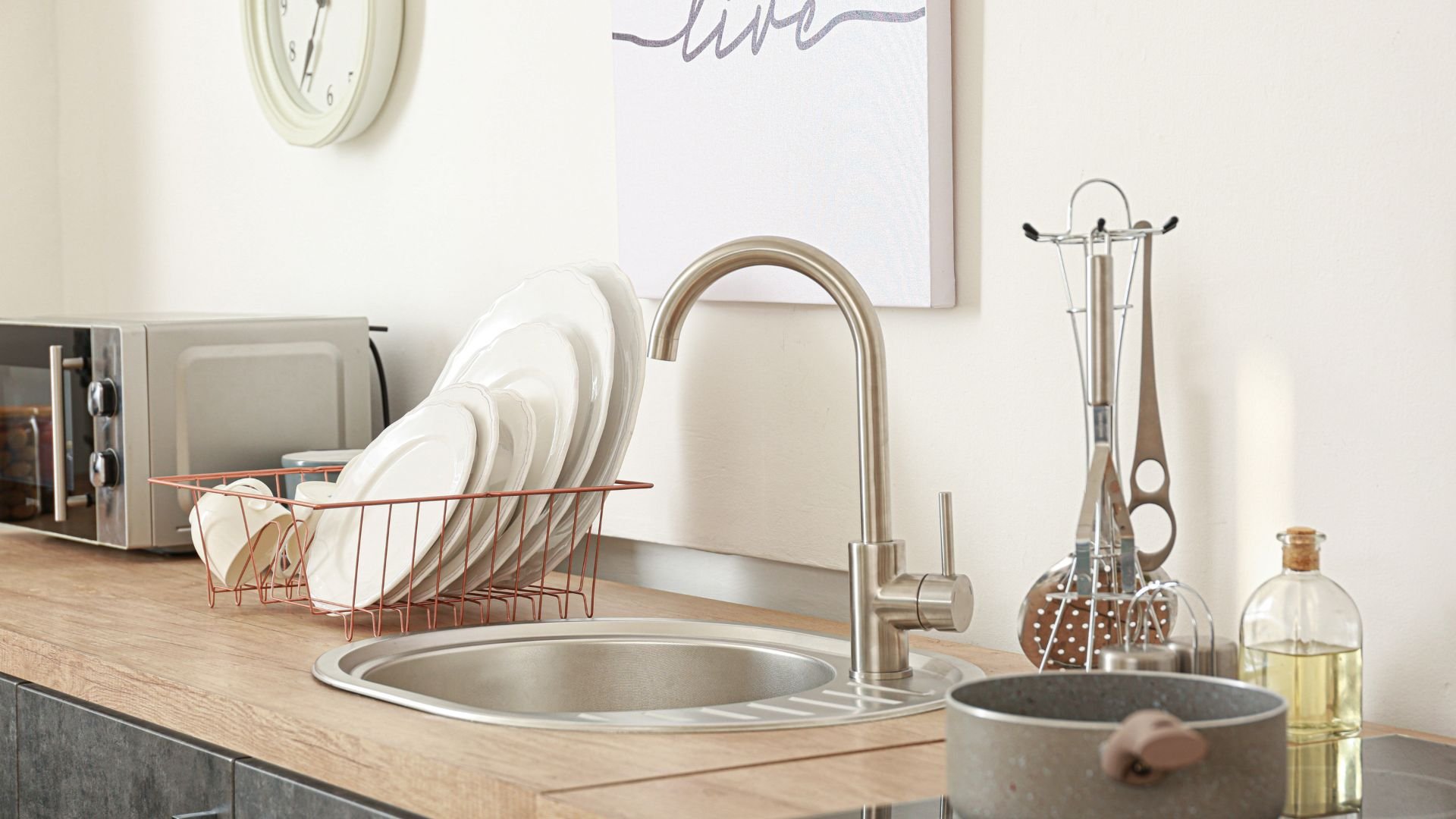 Modern kitchen sink with dishes, faucet, and cooking accessories