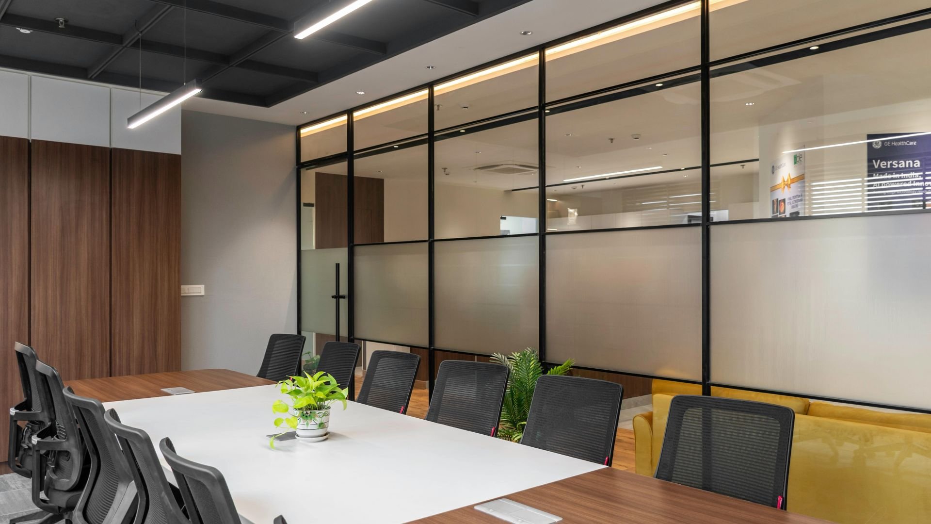 Modern conference room with glass partition, black chairs, and green plants